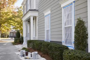 Home exterior prepared for painting with supplies and drop cloths in Clayton Apex area
